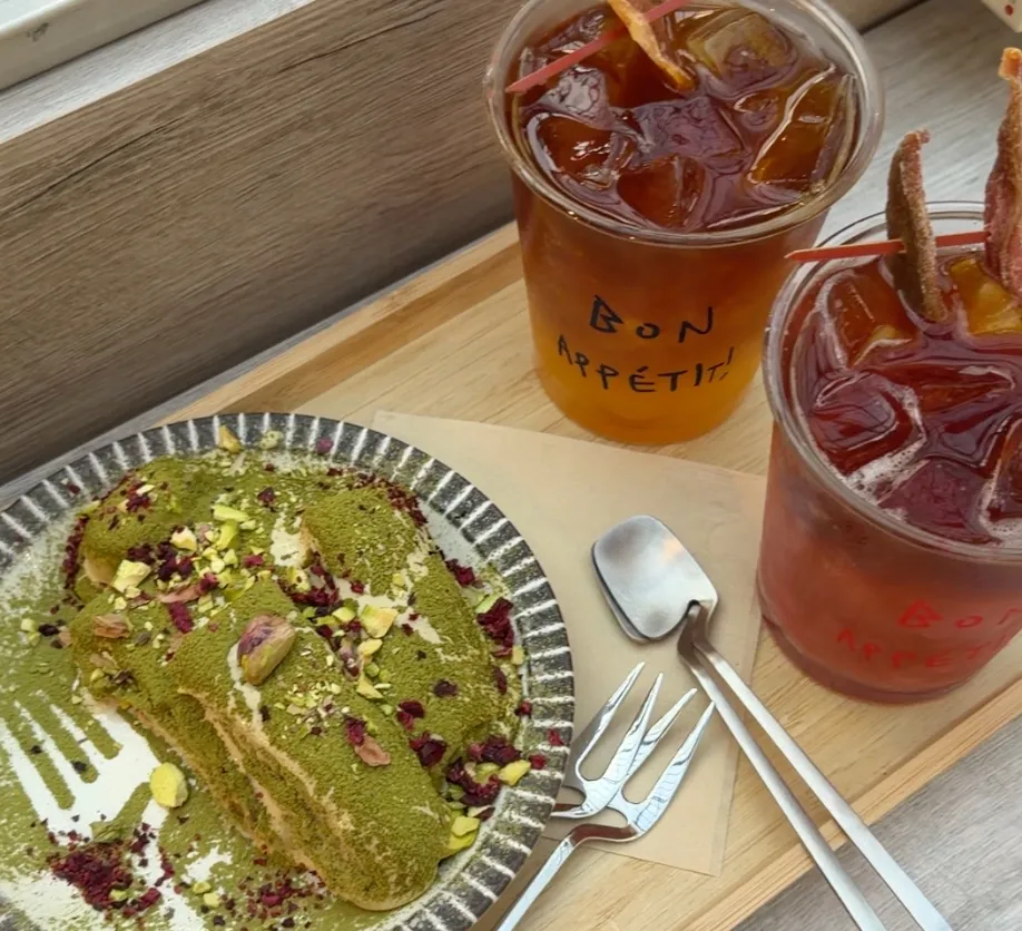 Eunice cafe 的抹茶提拉米蘇,鋪滿抹茶粉並點綴開心果碎與乾燥玫瑰,搭配兩杯手寫 BON APPÉTIT 的冰飲