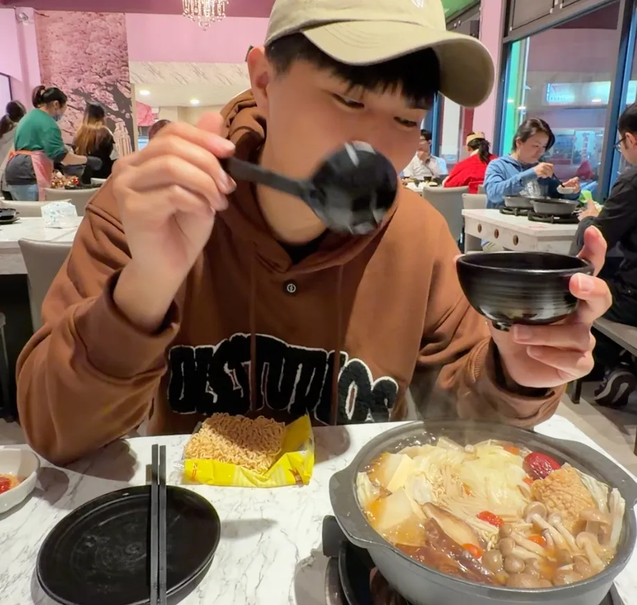 樂德火鍋的清湯鍋物,鍋裡有豆腐、鴻喜菇、紅棗與大白菜,旁邊配一包王子麵