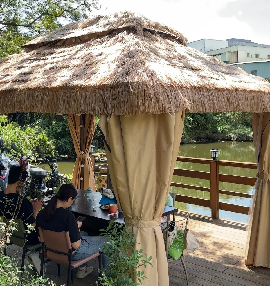 陶淬湖庭園咖啡的茅草涼亭包廂座位,就搭在小湖泊旁的木棧平台上,四周綠意環繞